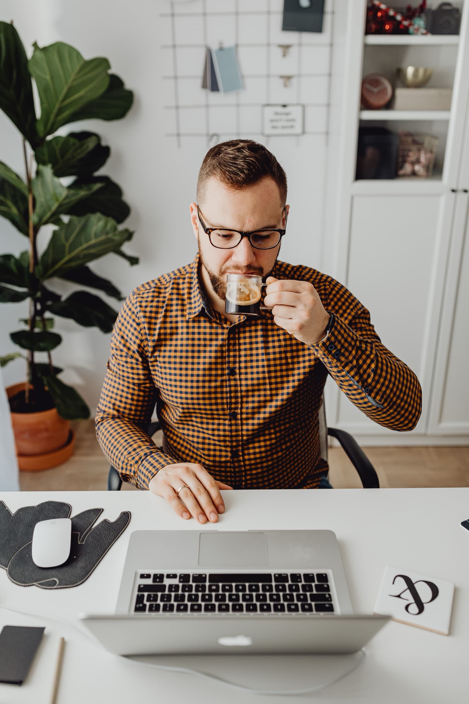 A property manager at his desk in the morning with coffee, glancing at his laptop